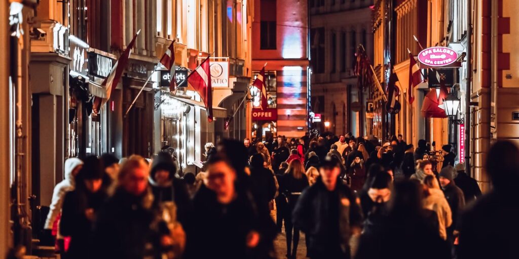 Levendige uitgaansstraat met verlichte gevels en bordjes in de avond