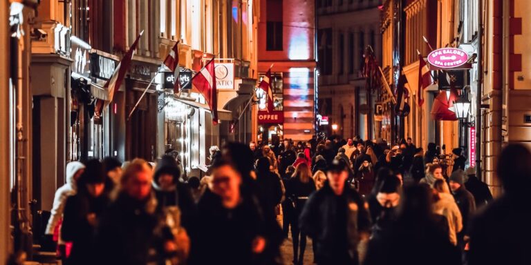 Levendige uitgaansstraat met verlichte gevels en bordjes in de avond
